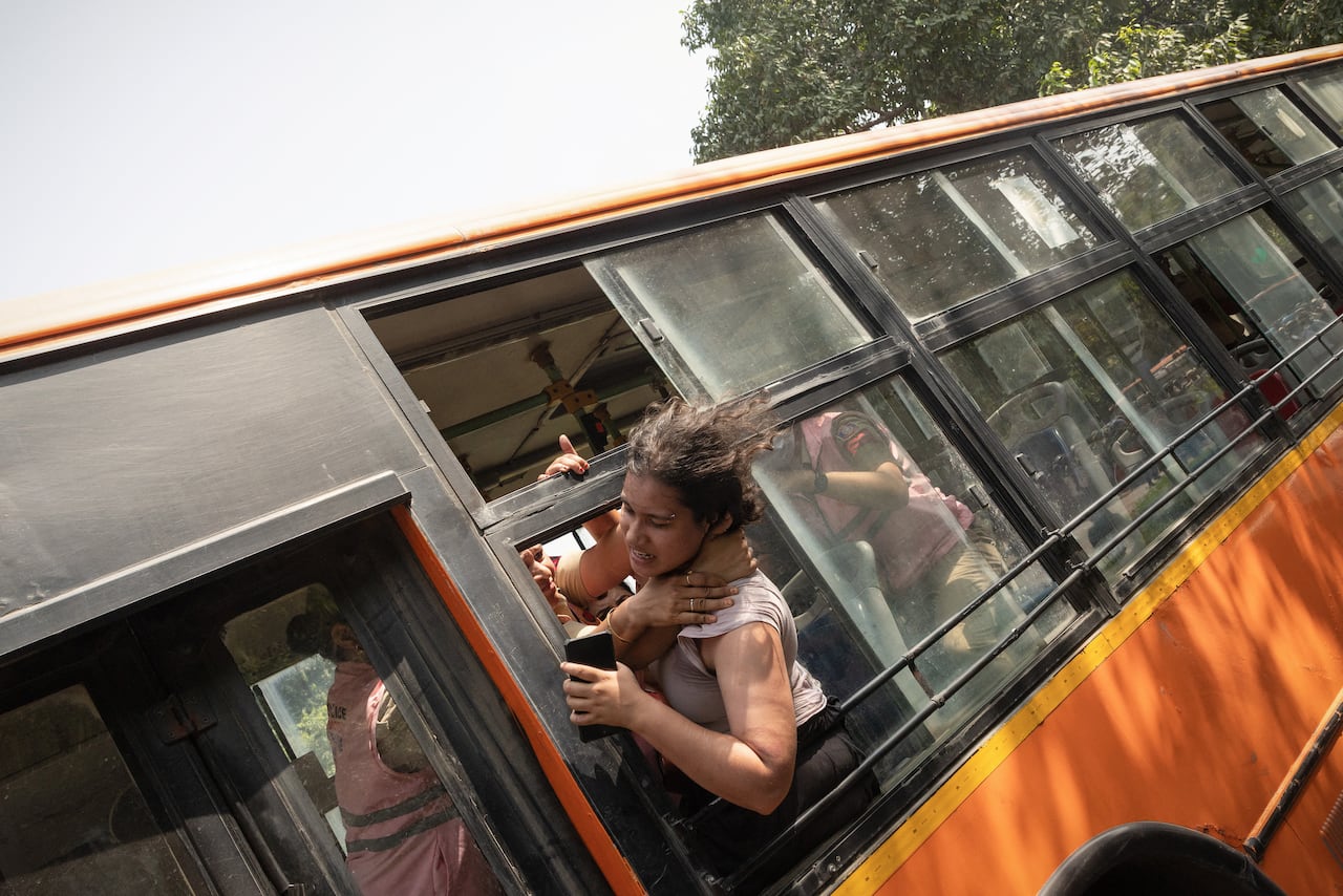 Policewomen try to stop a detained protestor to escape from a bus during a protest