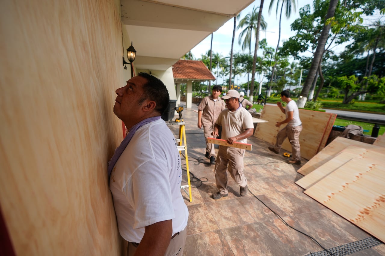 Workers board up windows outside a building.