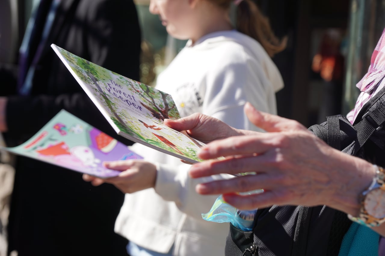 Several people's hands are seen as they pass books down a line.