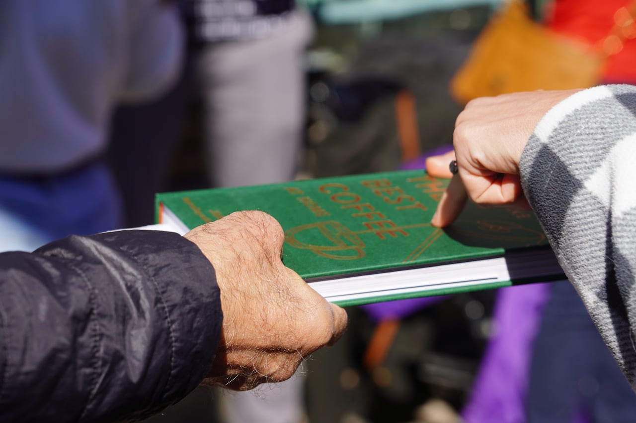 A greeb book passing between two people's hands.