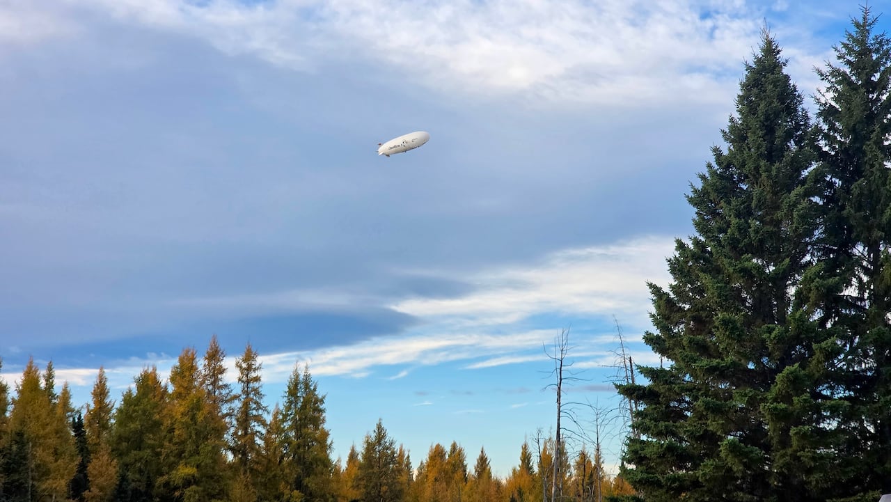 An airship hovering over trees.