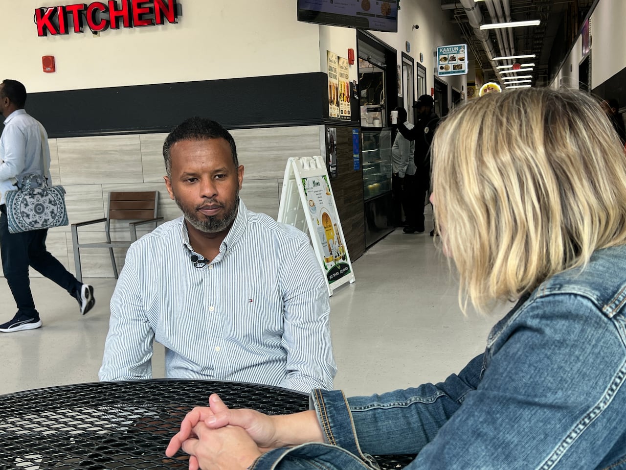 A man sits and talks with a reporter.