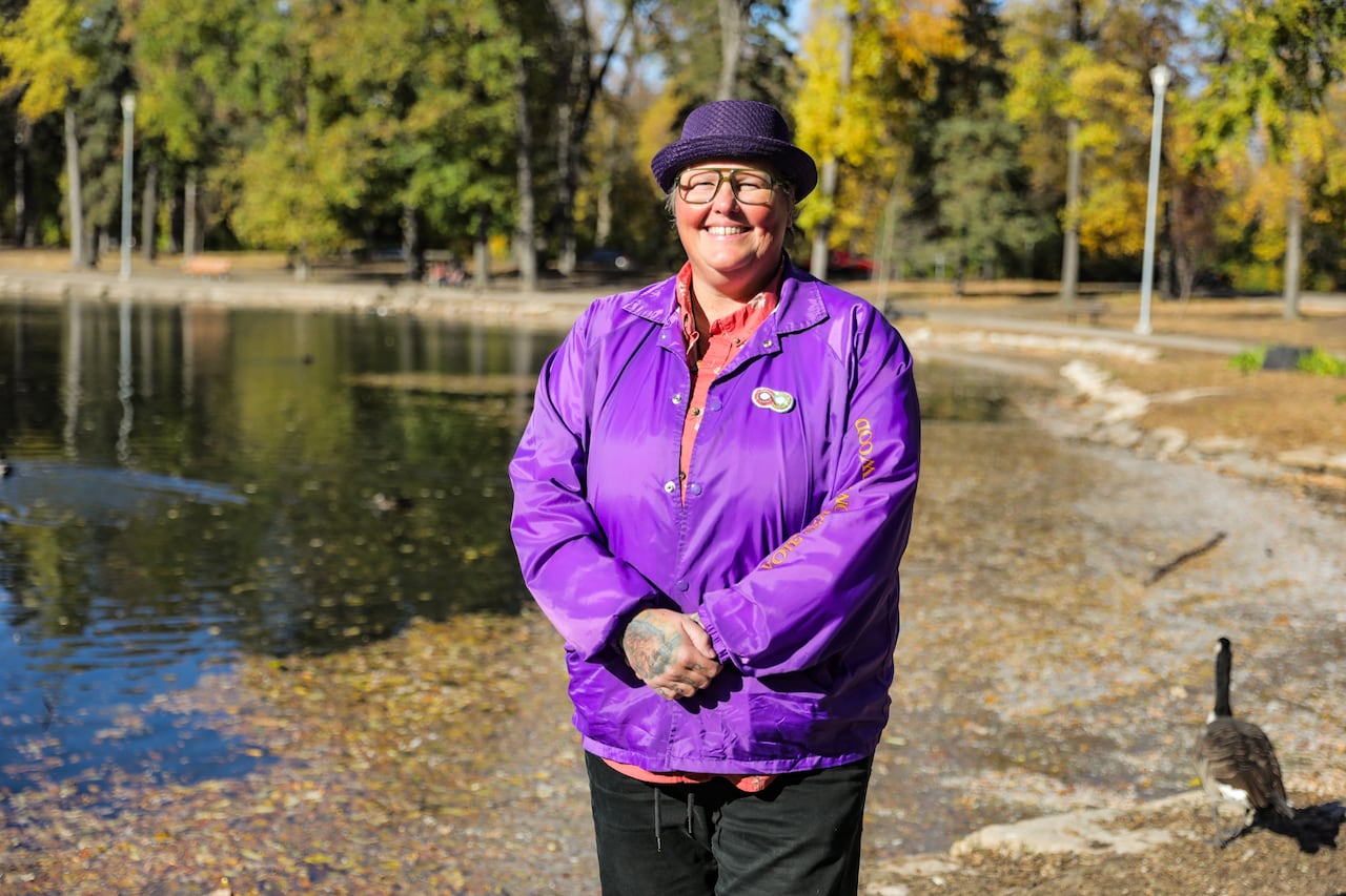 A woman in a purple coat standing next to a pond.