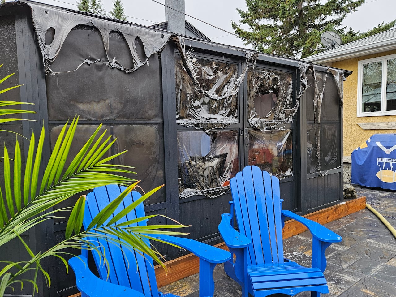 A backyard gazebo is stained black and partially melted from the heat of a fire in a neighbouring yard.