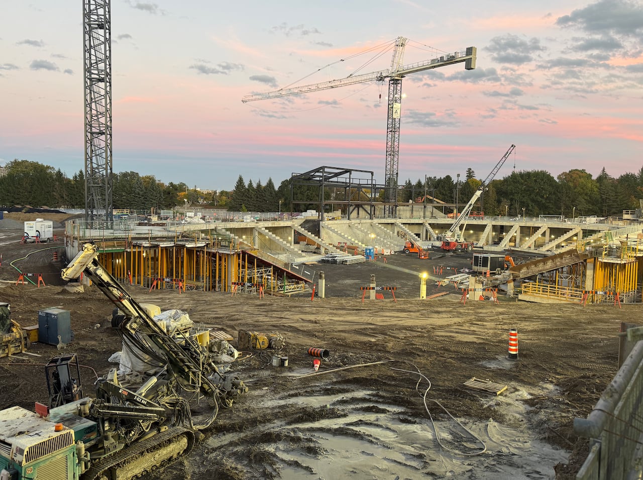 A new arena being built beside a football stadium on a cloudy early autumn day.