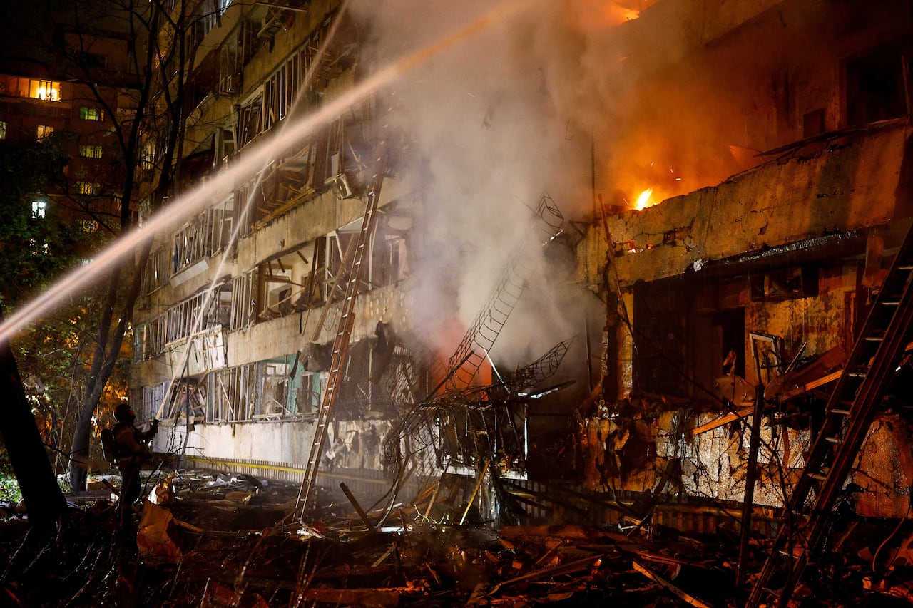 Firefighters spray water on a burning apartment building damaged by a missile attack.