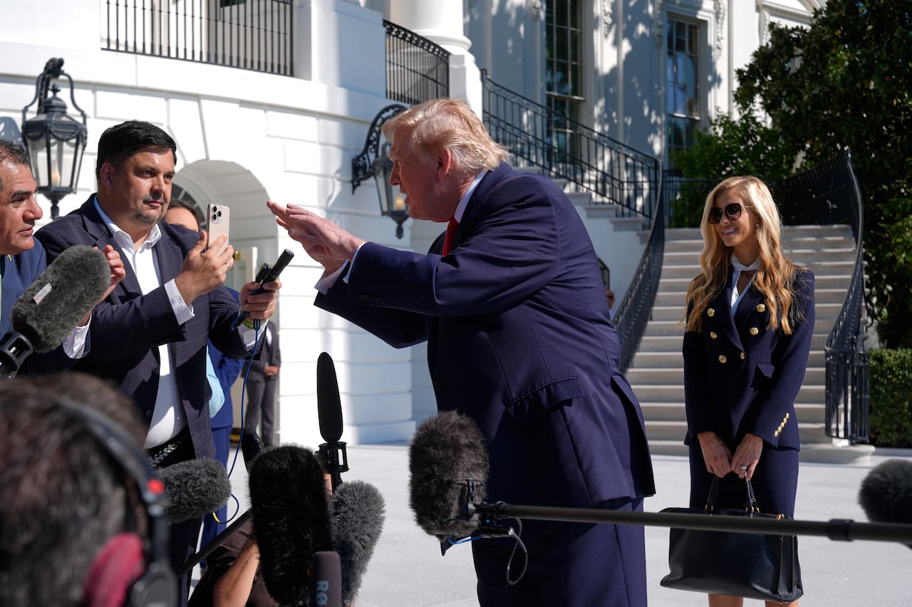 U.S. President Donald Trump gestures while speaking to reporters, with White House press secretary Katie Zacharia looking on from nearby.