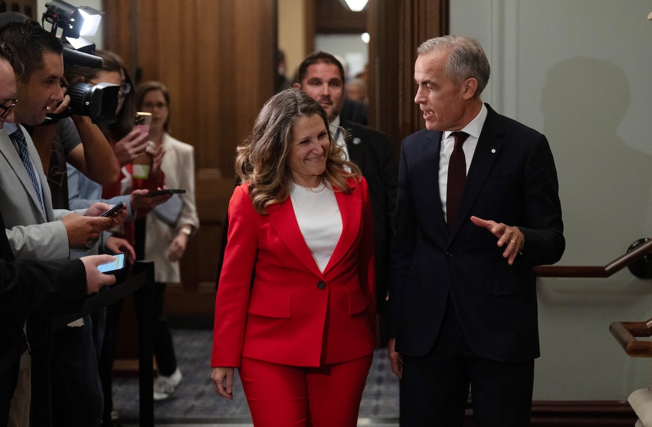 Both Chrystia Freeland and Mark Carney smile as they chat after leaving the cabinet room in the West Block.