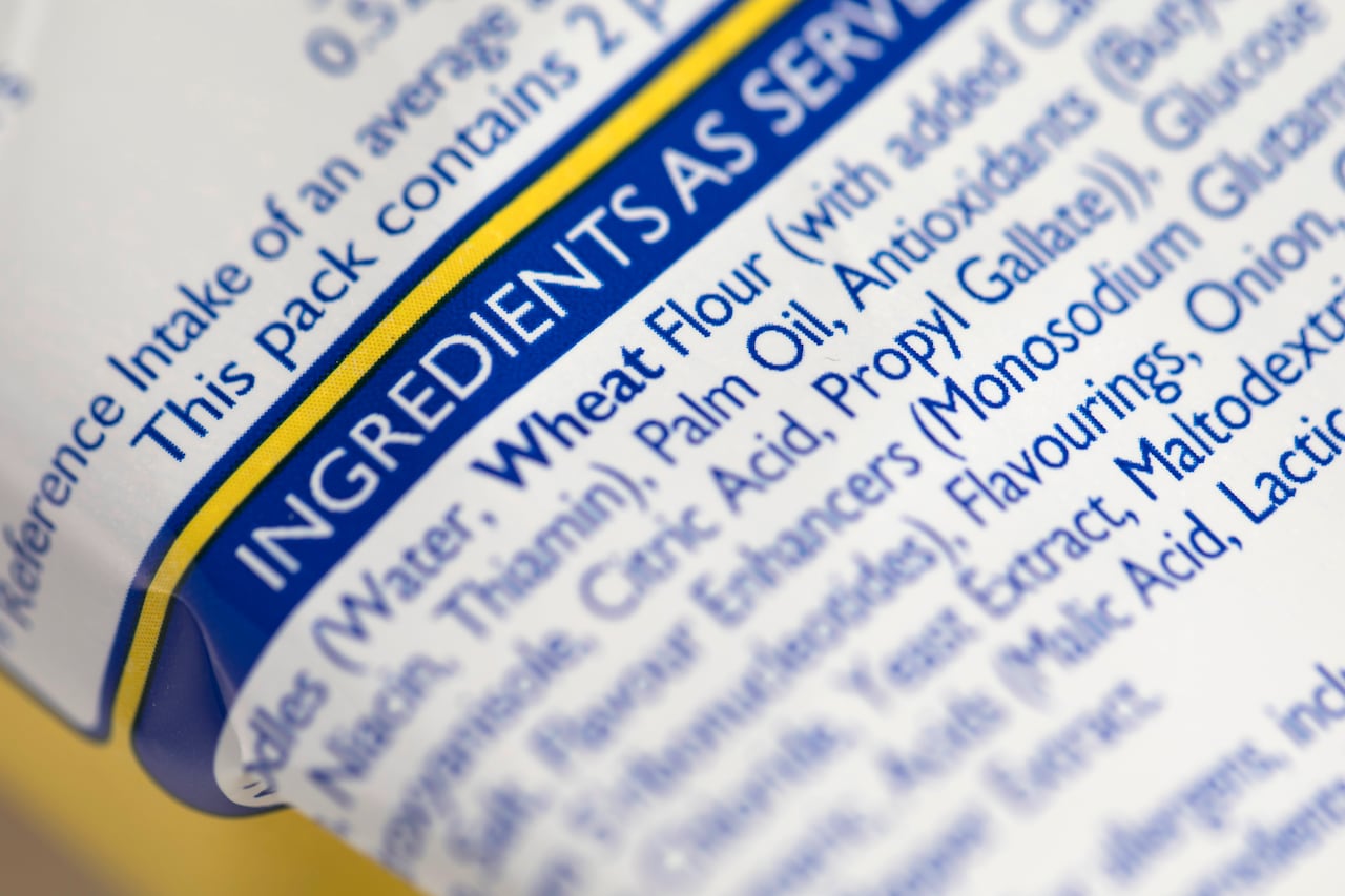 A close up on a white plastic package with a list of food ingredients typed in blue font.