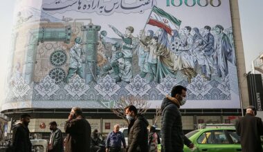 Pedestrians pass a giant banknote-style billboard showcasing state propaganda in central Tehran