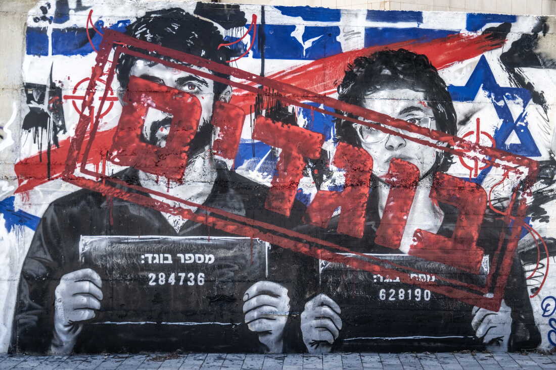A mural depicting Israeli filmmakers Yuval Abraham and Rachel Szor, directors of the documentary NAZA about Israeli military killing of Palestinians in the war in Gaza, has layers of graffiti on it, in Ashdod, Israel. Initially painted by an artist accusing the filmmakers of being "traitors," someone later scrawled the Hebrew word for "heroes" over it.