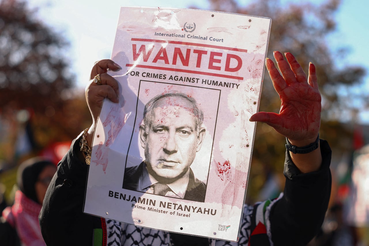 A protestor holding up a poster showing an arrest warrant of Israeli Prime Minister Benjamin Netanyahu.