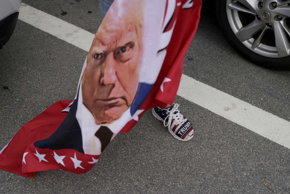 A flag featuring Donald Trump waves amid a group of supporters near Mar-a-Lago, Fla., in 2024.