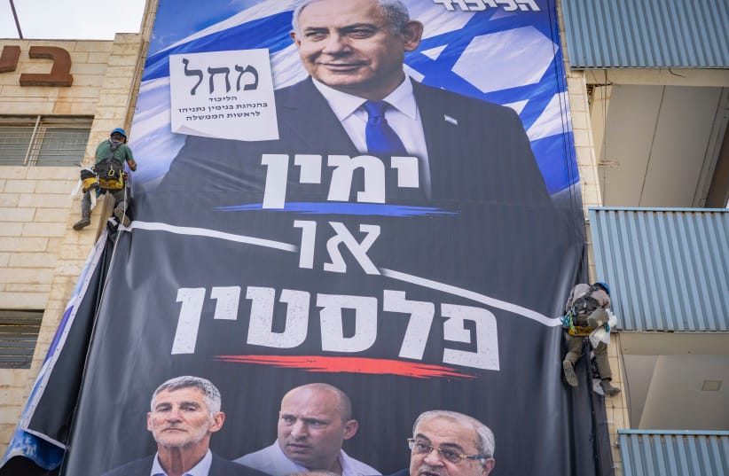 Workers hang a Likud party election campaign billboard featuring Prime Minister and Likud chairman Benjamin Netanyahu alongside opposition leaders, with the slogan “Right or Palestine,” on a building in Jerusalem, ahead of Israel’s upcoming general elections, October 14, 2026.