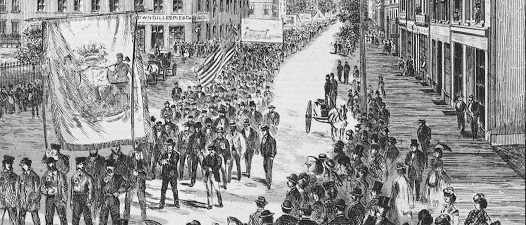 A black-and-white illustration shows a large procession of workers marching through a street carrying banners during the Nine-Hour Movement.