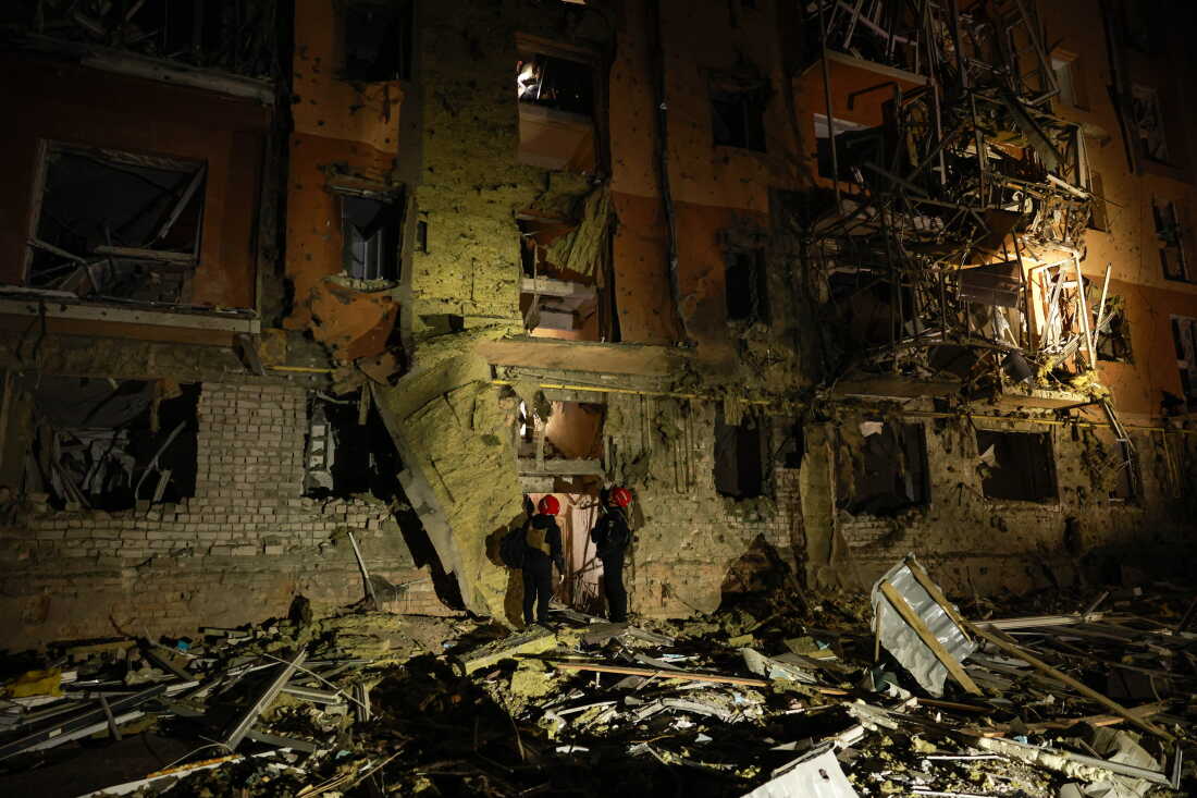 Rescue workers walk in front of a residential building damaged by a Russian airstrike in Zaporizhzhia, Ukraine, on Saturday.