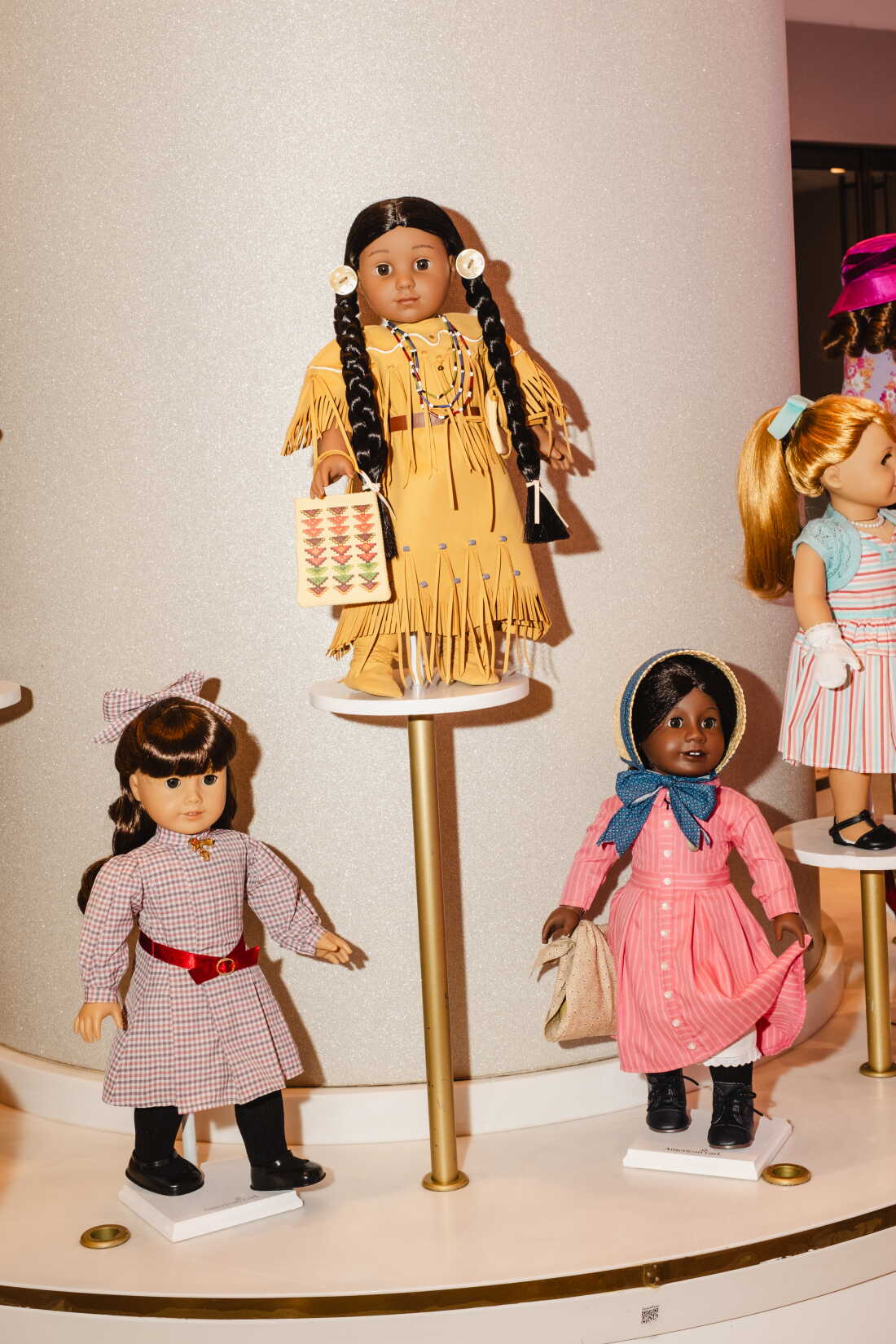 American Girl dolls Samantha (from left), Kaya and Addy stand on display stands.