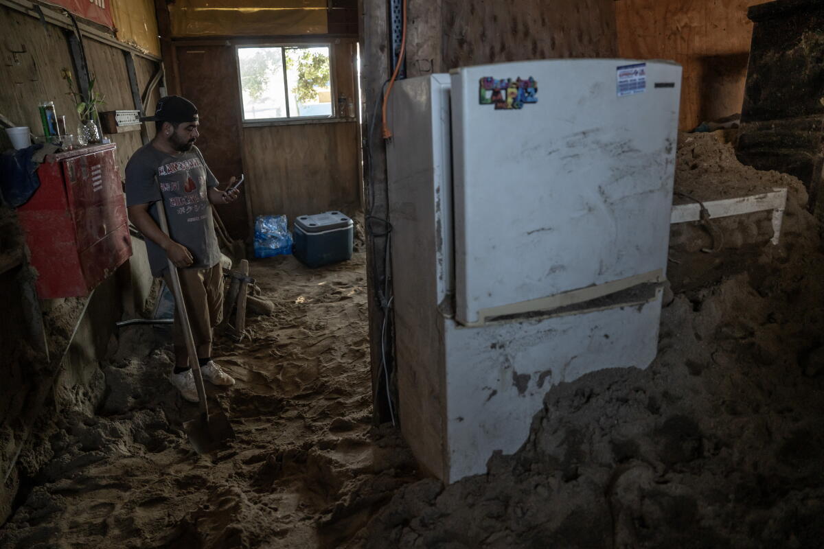 Residents of the Maneadero community clean mud and debris from their flooded homes
