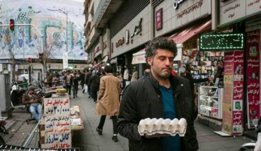 A man carries a tray of eggs through a Tehran market as staple food prices surge, pushing basic items beyond the reach of many households — December 2025