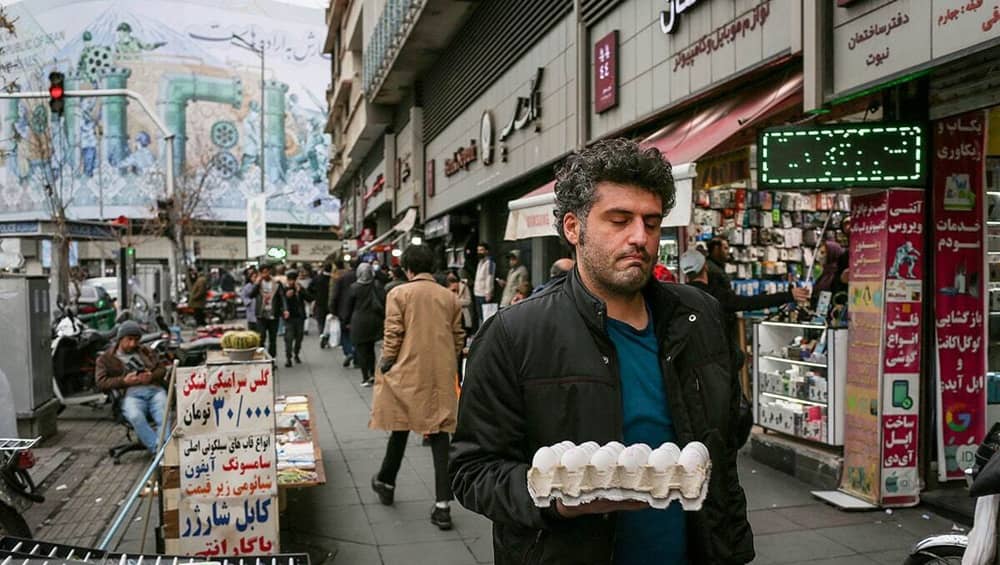 A man carries a tray of eggs through a Tehran market as staple food prices surge, pushing basic items beyond the reach of many households — December 2025