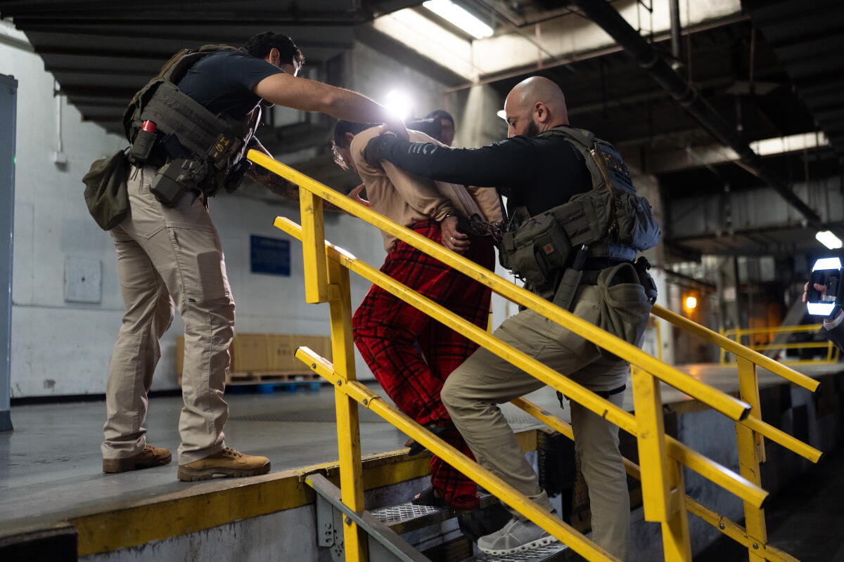 Homeland Security Investigations task force officers escort a suspect.
