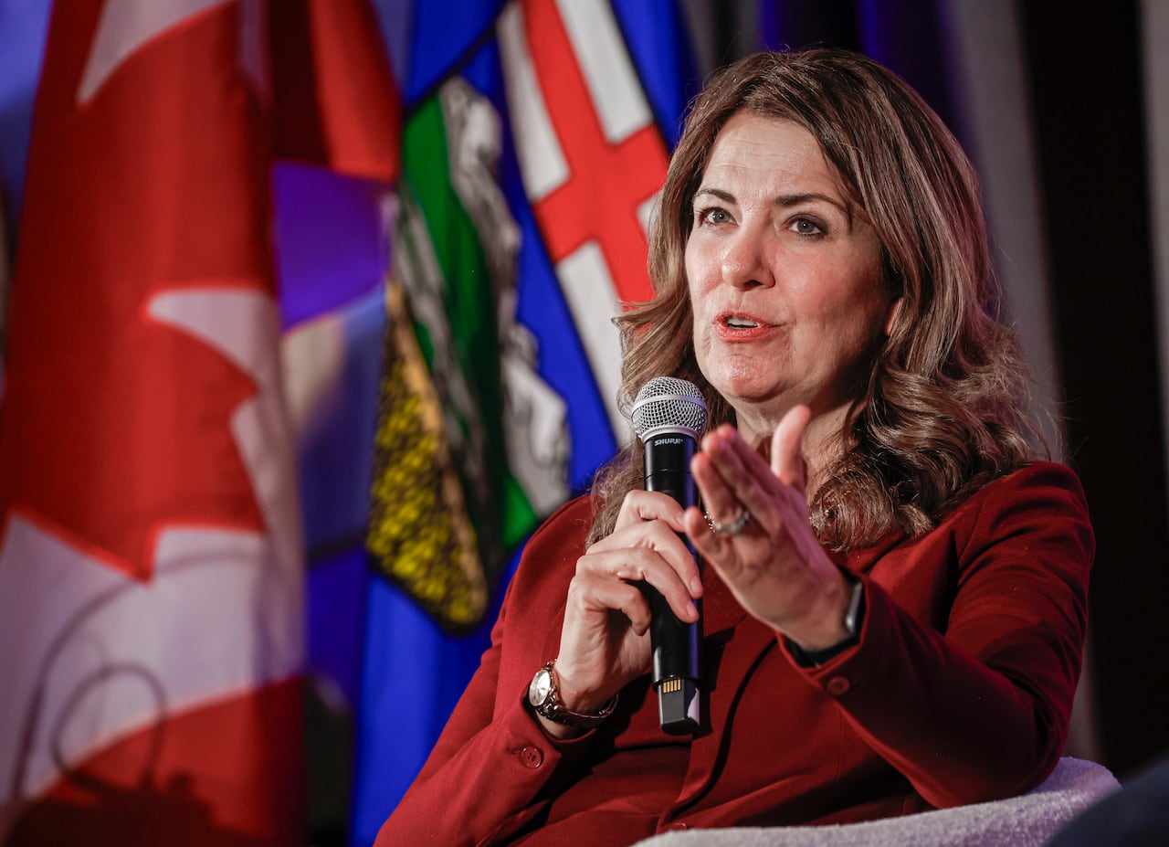 A woman speaks in front of two flags.