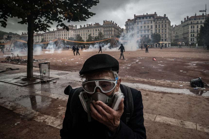 An elderly man uses a gas mask to protect from the smoke from tear gas during demonstration against the