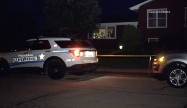 A Mundelein police squad car parked outside a home with crime scene tape at night