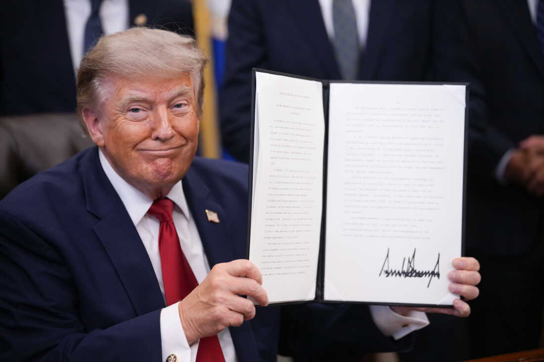 In this file photo from July 2026, President Trump shows off an executive order he signed in the Oval Office of the White House.