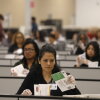 Election workers who are seated and wearing clear gloves process ballots for the California state primary.