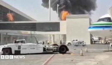 Somebody holding up a smart-phone in their right hand. The screen is black with 'Revolut' written in white letters.