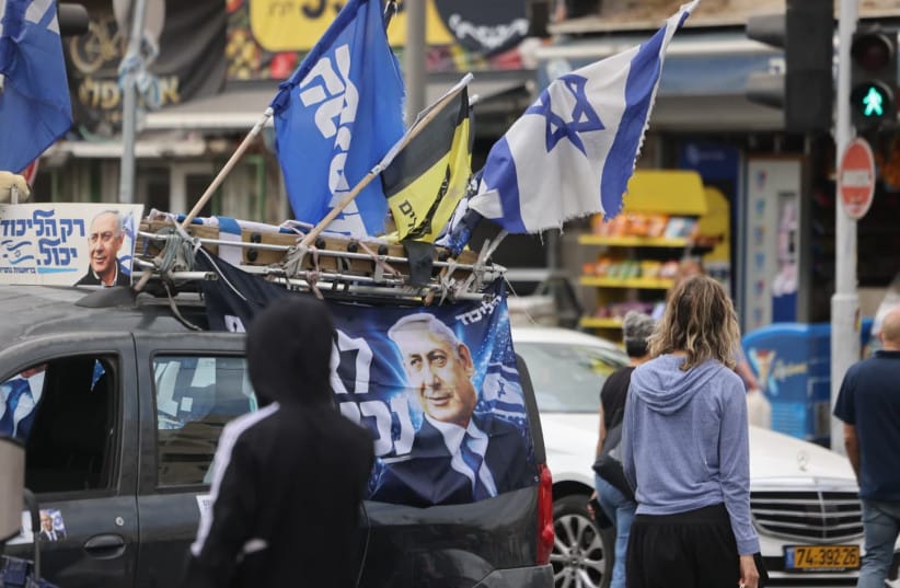 People walk past a vehicle displaying Likud campaign posters featuring Prime Minister Benjamin Netanyahu, in Jerusalem's Mahane Yehuda market, October 16, 2026