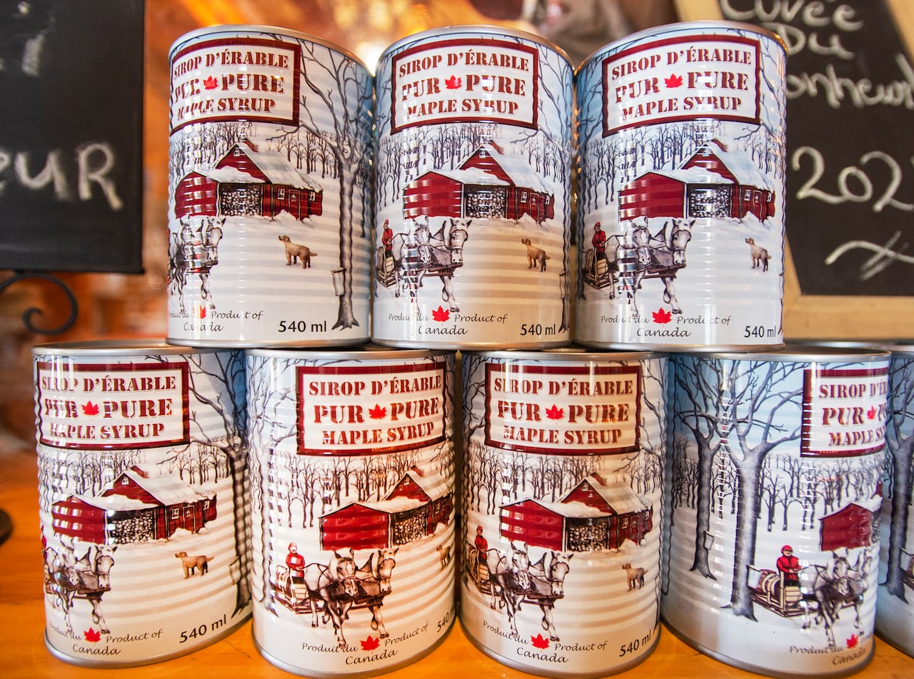 Cans of maple syrup are stacked on top of each other.