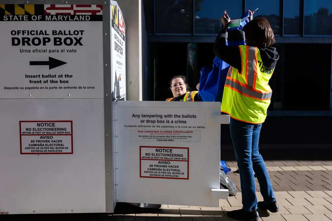 Election workers remove ballots from a drop box outside the polling center at the Silver Spring Civic Building on Oct. 22 in Silver Spring, Md.