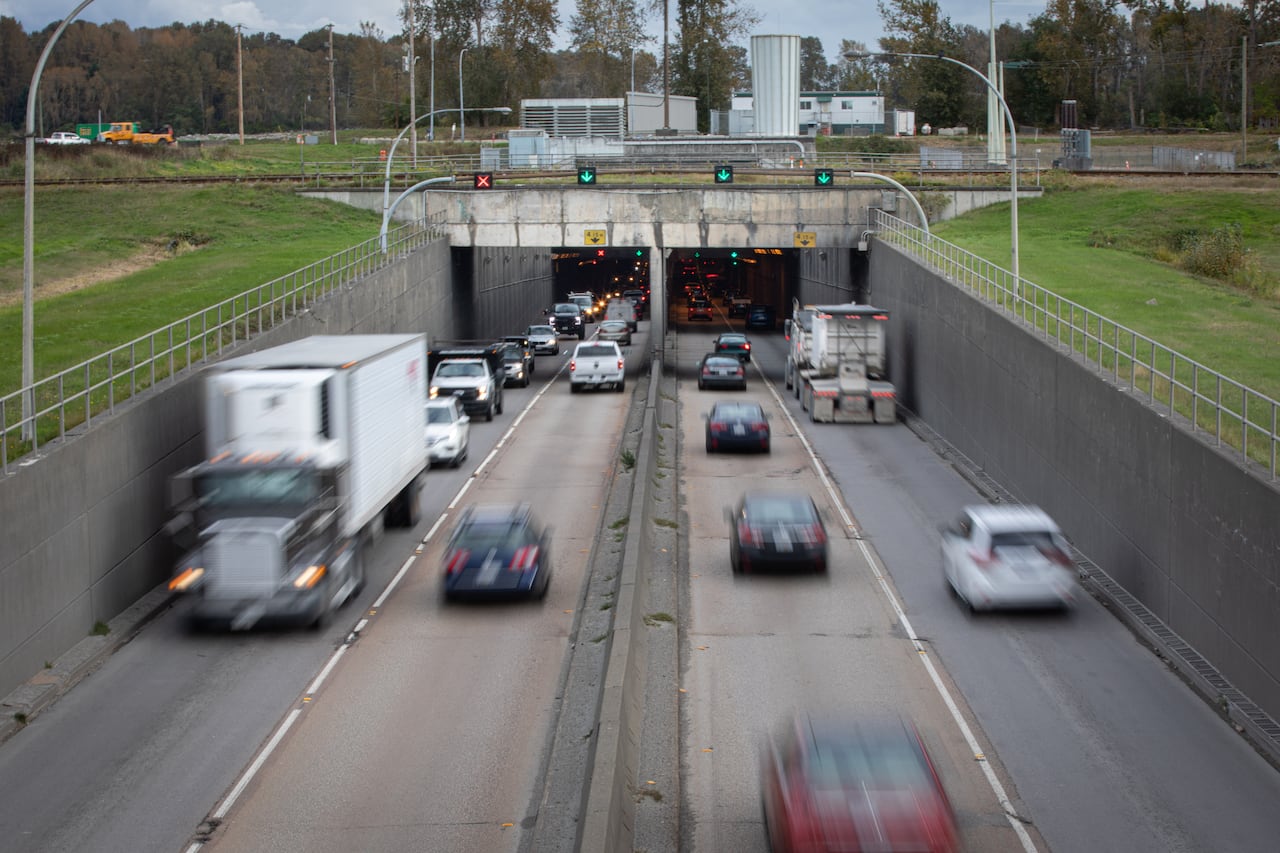 A long exposure shot of cars entering and exiting a tunnel in the ground. The vehicles show a motion blur.