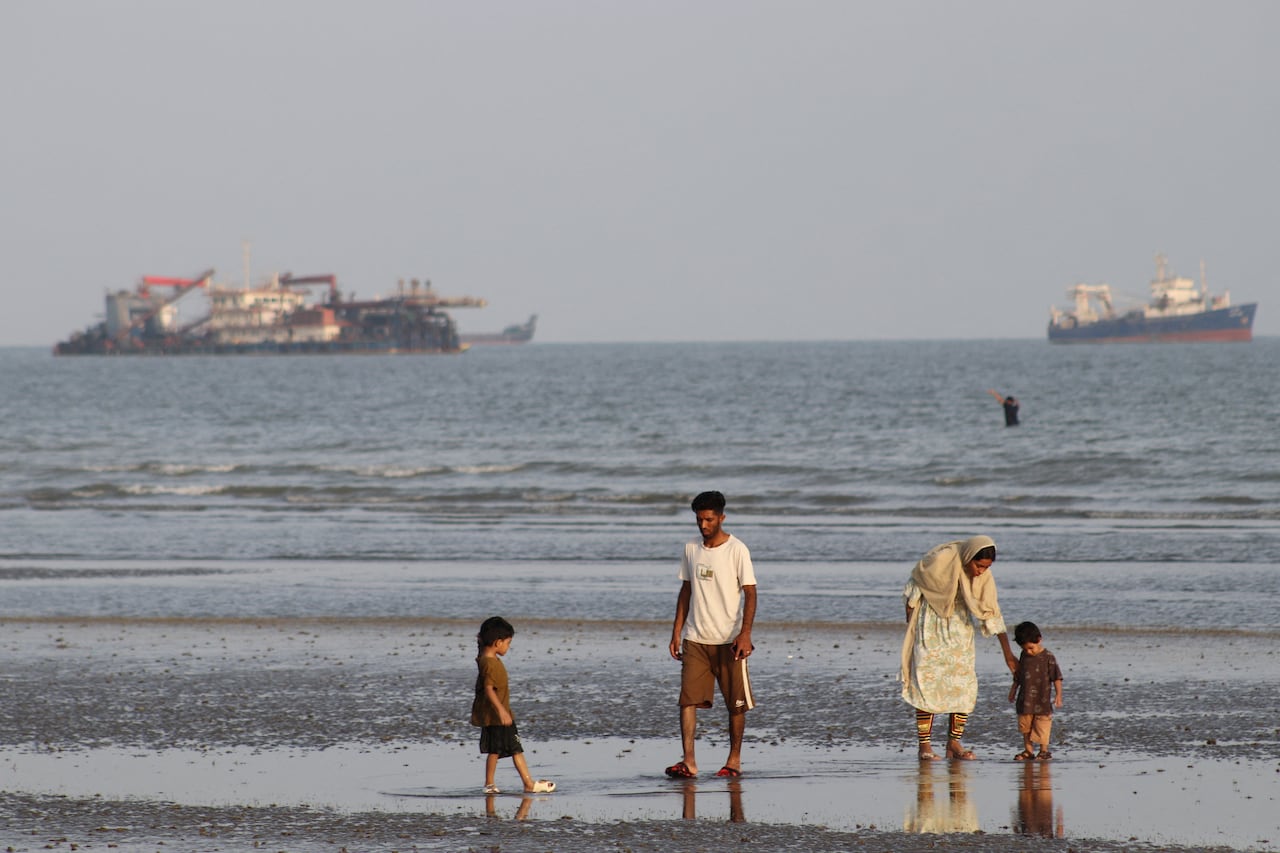 People on the beach, with vessels in the Strait of Hormuz visible near the beach of Bandar Abbas, Iran, October 13, 2026.