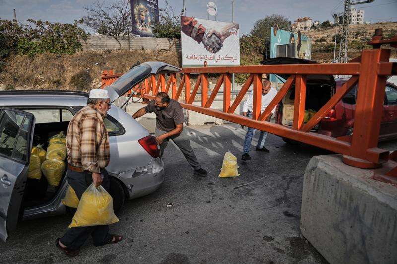 Palestinians transport bags of semolina past a military gate closed to vehicles during an Israeli army operation in Hebron, in the occupied West Bank, Saturday, Oct. 24, 2026, a day after a Palestinian shooting attack in the area. (AP Photo/Mahmoud Illean)