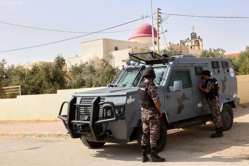 Jordanian police officers stand beside an armored vehicle outside St. George's Greek Orthodox Church a day after gunmen opened fire during a funeral in the village of Hamoud, in Jordan's Karak governorate, Saturday, Oct. 24, 2026. (AP Photo/Raad Adayleh)