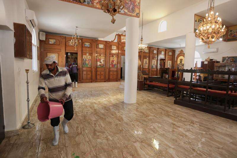 A worker pours water onto the floor while cleaning St. George's Greek Orthodox Church a day after gunmen opened fire during a funeral in the village of Hamoud, in Jordan's Karak governorate, Saturday, Oct. 24, 2026. (AP Photo/Raad Adayleh)