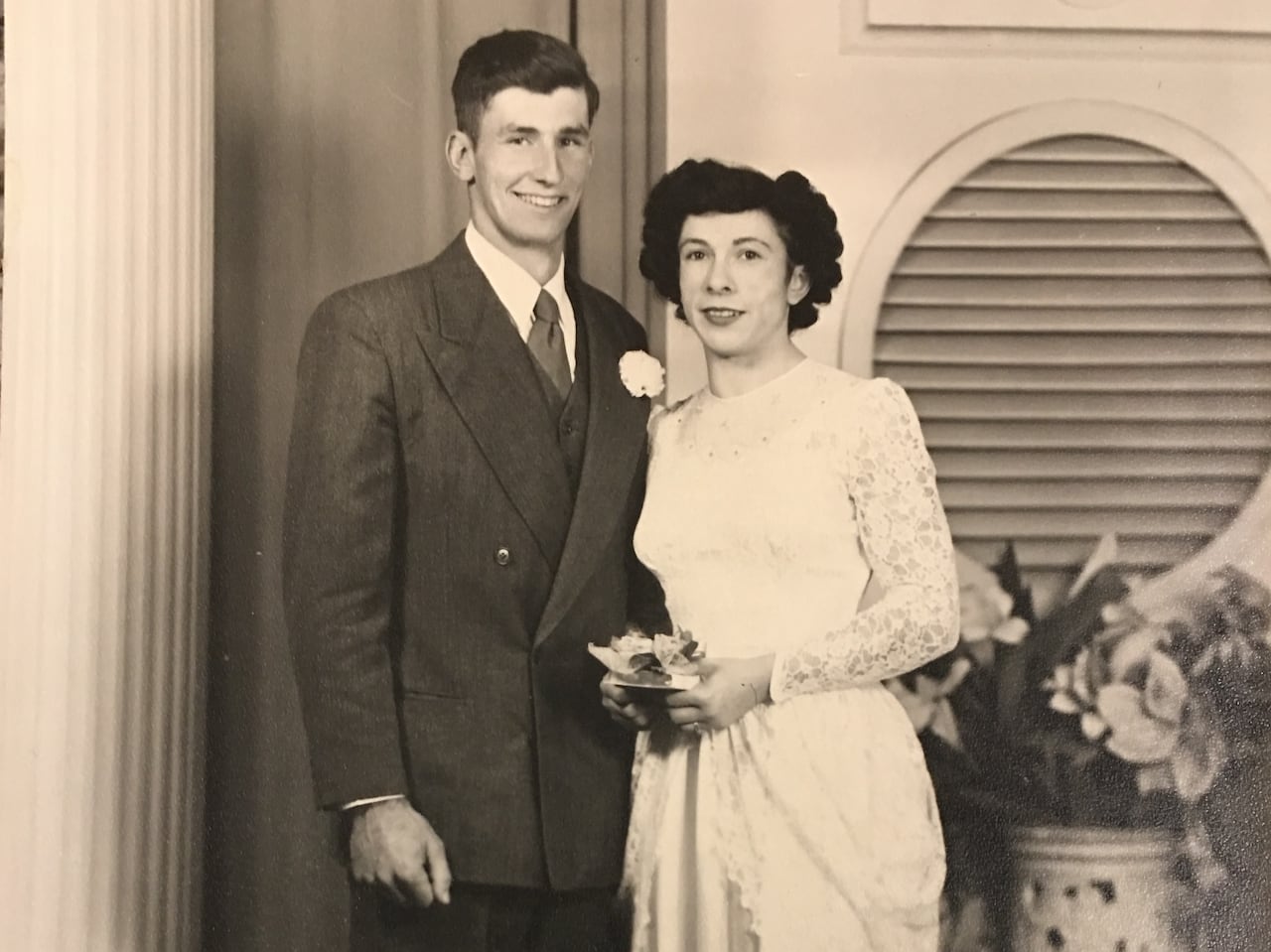 An old black-and-white studio portrait of a man in a suit and a woman in a white dress.