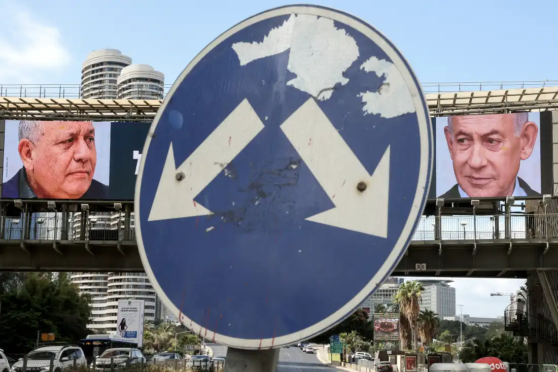 A road sign stands in front of a large billboard featuring Israel's Prime Minister Benjamin Netanyahu (right) of the Likud party and his main center-right opponent, former military chief Gadi Eisenkot, in Ramat Gan, Israel.