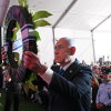 Israeli Prime Minister Benjamin Netanyahu holds up a wreath as he places it during a state memorial ceremony in memory of those killed in the October 7, 2023, Hamas-led attack on Israel, at Mount Herzl cemetery in Jerusalem on October 5. Rows of people are standing behind him.