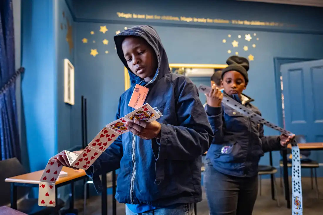 Students examine a set of trick playing cards during a class at the College of Magic in Cape Town, South Africa.