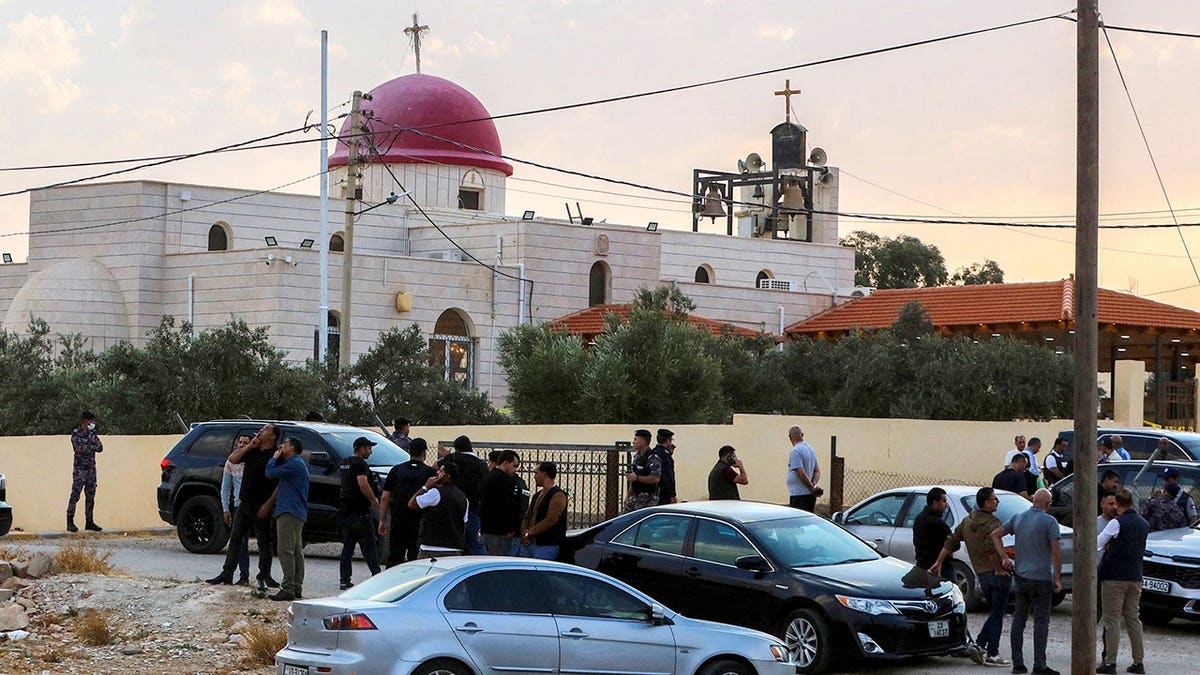 People and security forces gather outside a Greek Orthodox church in Hammoud, Jordan.