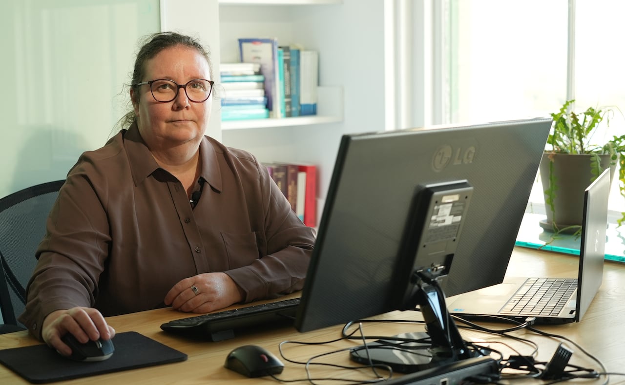 Woman seated at desk, in front of a computer.