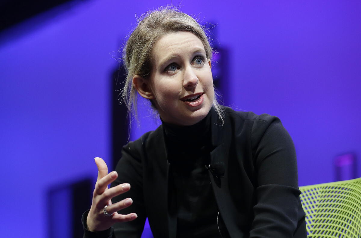 A woman in black speaks at a business conference.