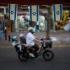 Israeli flags hang at a shop as a bicyclist carrying children passes by, Wednesday, Oct. 28, 2026, in Tel Aviv, Israel, the day after Israel's general election.