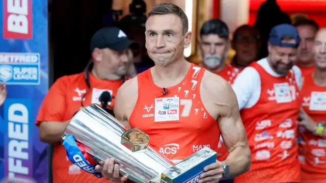 Sir Kevin Sinfield carries the Super League trophy into Old Trafford