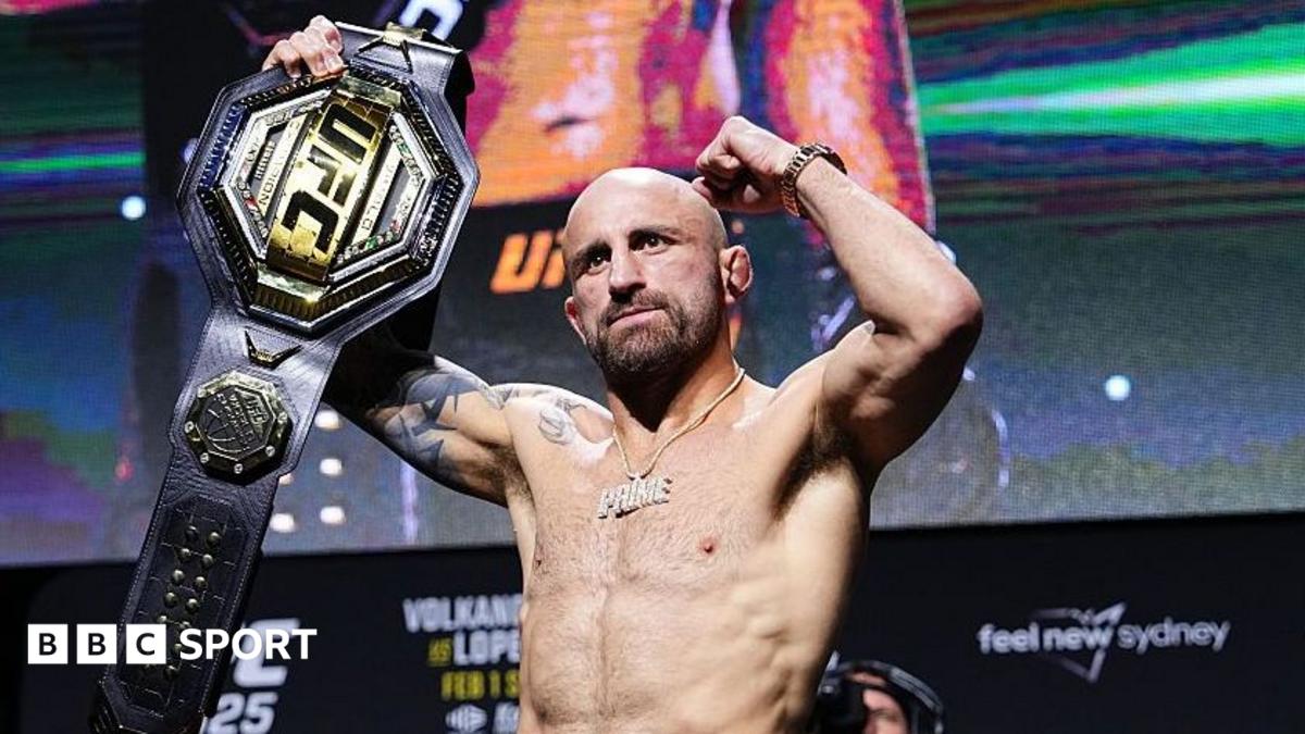 Alexander Volkanovski raises his UFC featherweight title after a news conference
