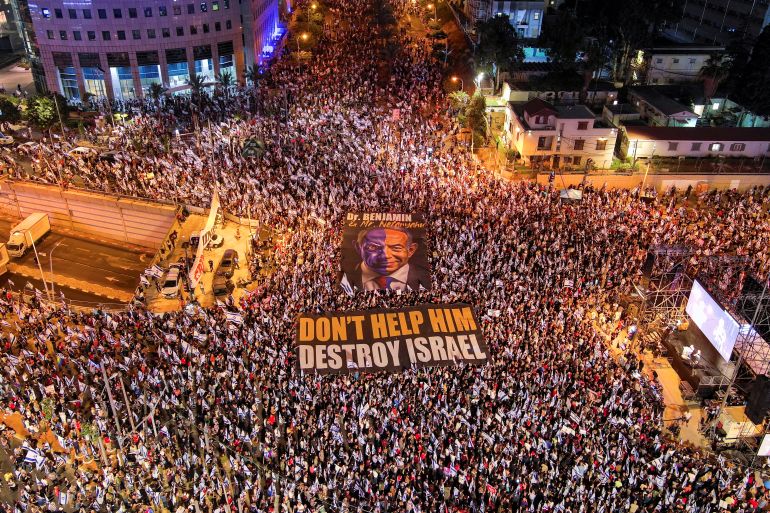 An aerial view shows protesters holding signs, one which depicts Israeli Prime Minister Benjamin Netanyahu and the other with the words "don't help him destroy Israel" as they attend a demonstration against his nationalist coalition government's judicial overhaul, in Tel Aviv, Israel May 27, 2023. REUTERS/Ilan Rosenberg TPX IMAGES OF THE DAY